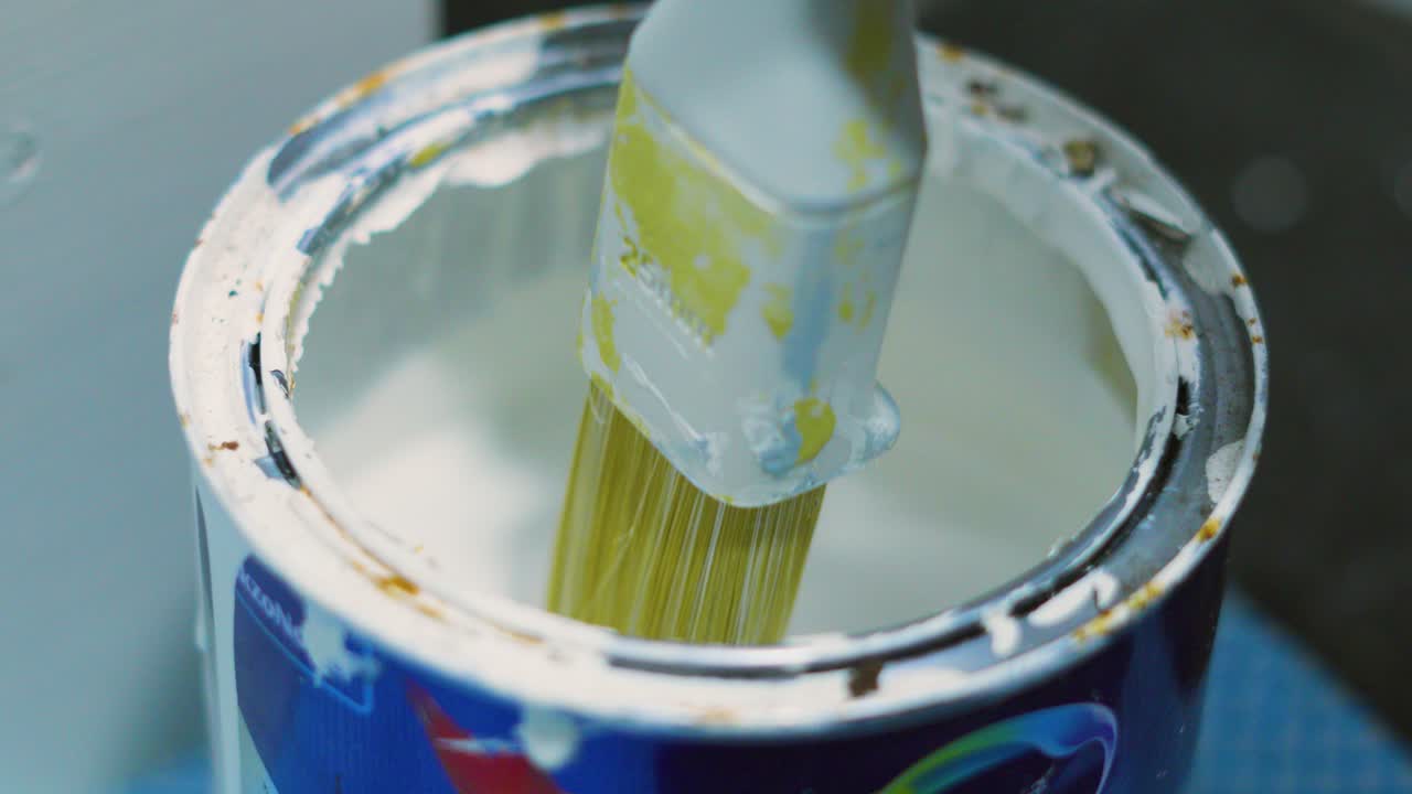Close Up of Pot of White Paint with Brush Being Dipped Repeatedly Before Applying to Wall. Home Decorating DIY Footage 4K