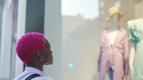 person with bright pink hair looking at a shop window display