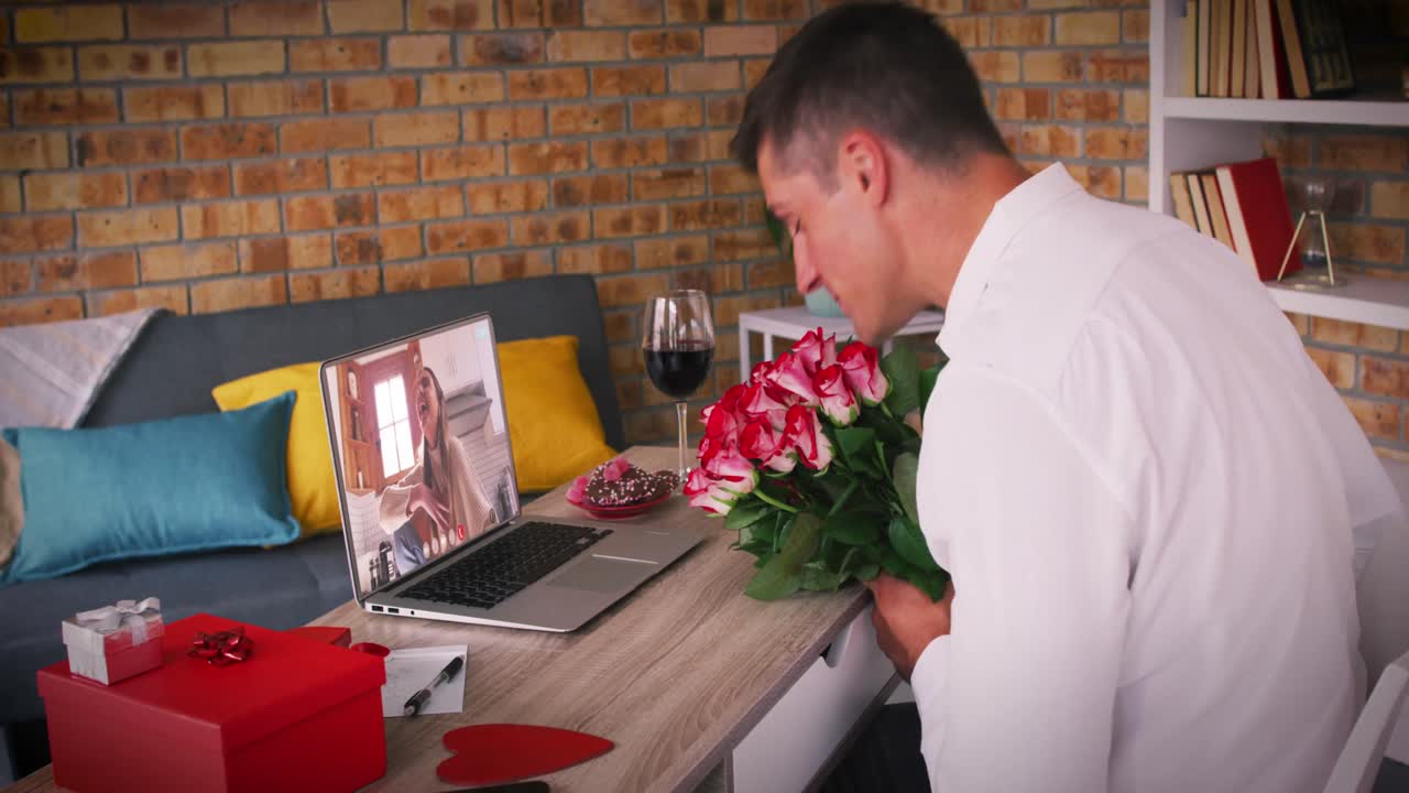 발렌타인 데이트의 백인 커플 비디오 통화 여자 노트북 화면에서 웃는 남자 꽃을 들고