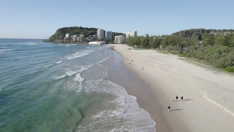 People-Walking-In-The-Sandy-Stretch-Of-Burleigh-Beach-On-A-Sunny-Day-In-Gold-Coast,-QLD,-Australia