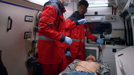 multi ethnic paramedics giving first aid help to man in emergency car