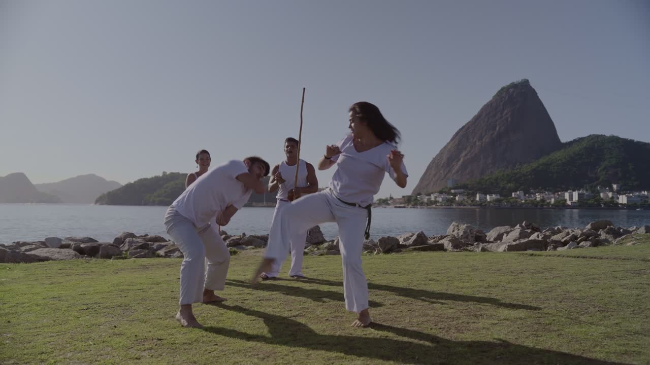 People practicing capoeira outdoors with Sugarloaf Mountain in Rio de Janeiro