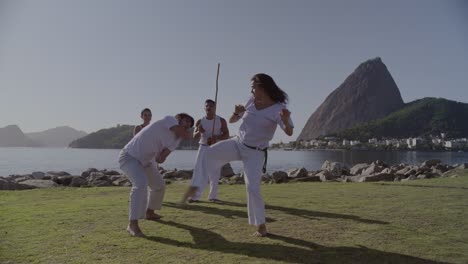 People practicing capoeira outdoors with Sugarloaf Mountain in Rio de Janeiro