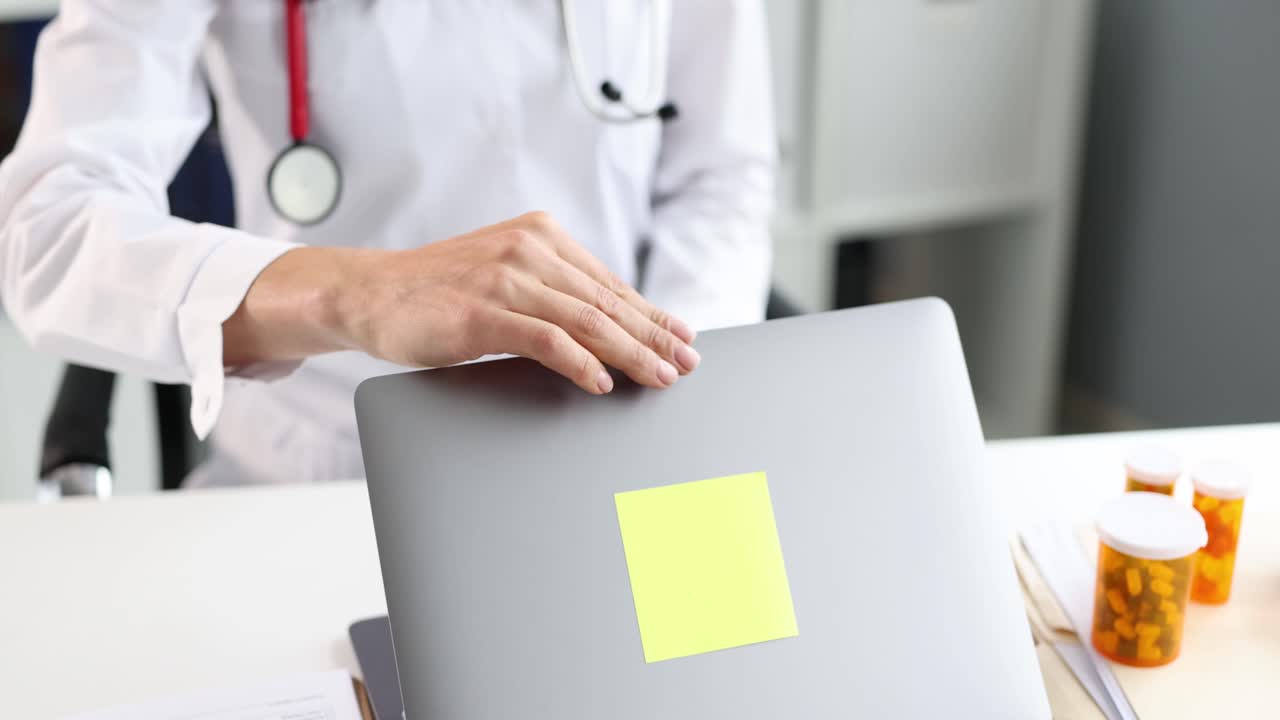 Video 4K al rallentatore di un dottore che chiude il coperchio di un laptop acceso nello studio di una clinica.