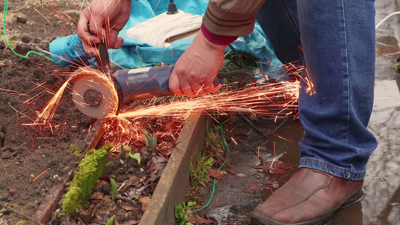un hombre con una molienda angular corta un invernadero de metal oxidado.