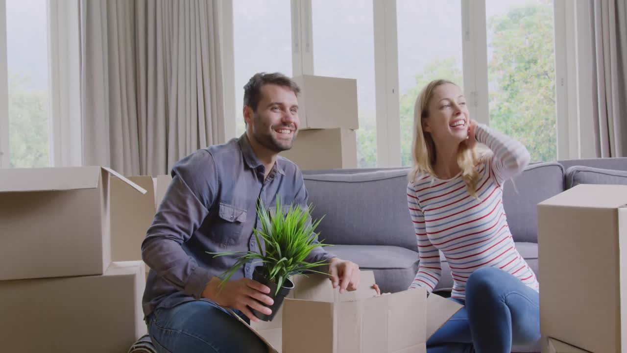 Couple unpacking cardboard box in new home 4k