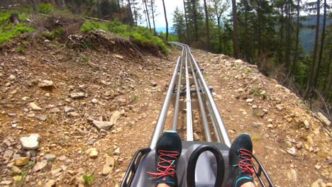 foto pov gopro de un hombre montado en una montaña rusa al aire libre en una ladera rocosa rodeada de árboles en dolní morava, república checa con vistas al campo