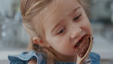 niña feliz lamiendo cuchara degustando delicioso pudín de chocolate disfrutando de golosinas caseras en la cocina 4k