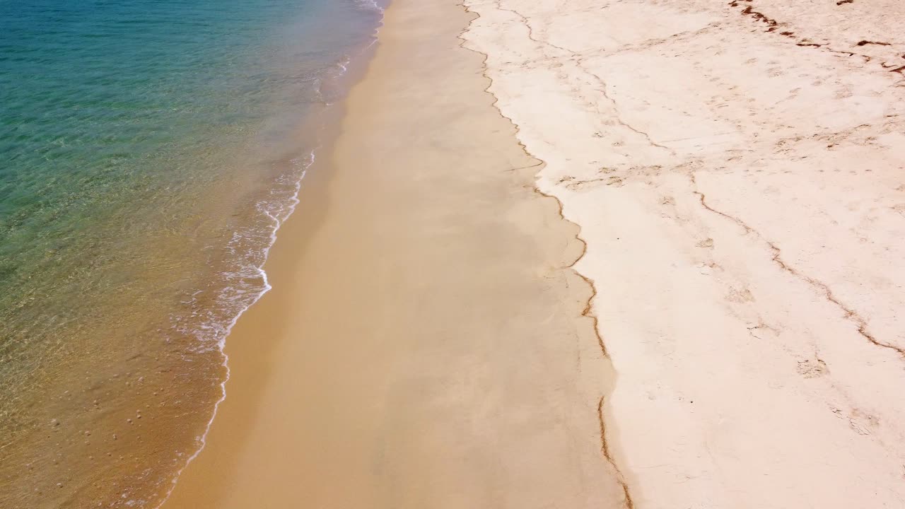 Luftfoto af sandstrand og hav med bølger