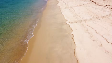 aerial view of sandy beach and ocean with waves