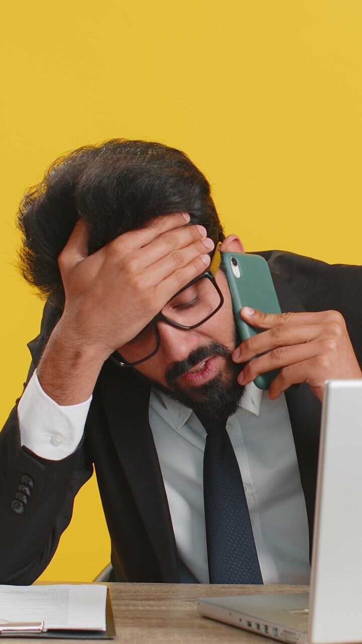 Un uomo d'affari indiano stanco e addormentato che ha avuto una noiosa conversazione su smartphone con un cliente.