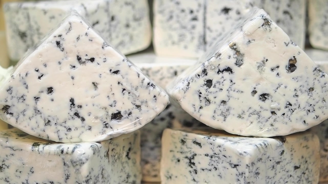 Spicchi di formaggio erborinato gourmet avvolti nella plastica in esposizione