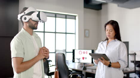 using vr headset, man interacting while woman holding tablet in modern office