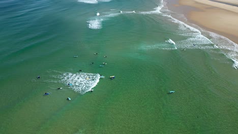Surfers-catch-waves-at-Biscarrosse-Beach-France-in-the-Western-coast,-Aerial-pan-left-shot