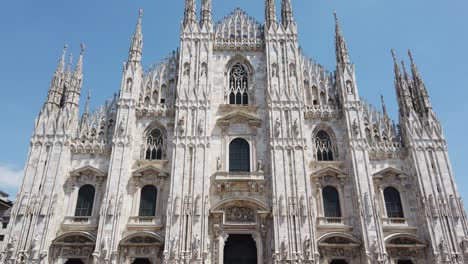 milan duomo cathedral tilt up front view main facade gothic style against blue sly, tilt up