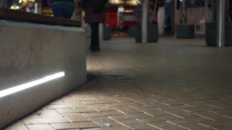 toma nocturna estática que muestra a dos mujeres caminando en una zona peatonal