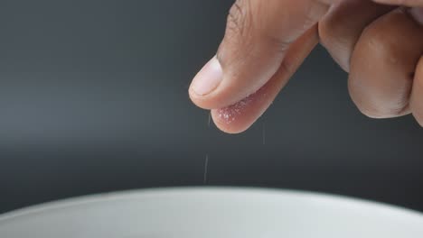 close-up of a hand sprinkling salt into a bowl