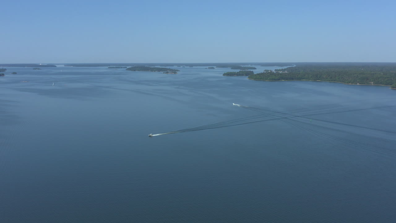 Aerial panoramic wide shot of a speed boat in a blue sea archipelago