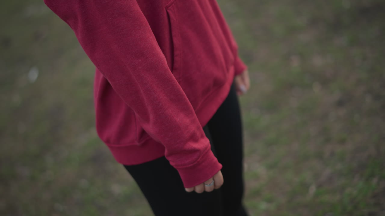 Hands Adjusting Hoodie, Person Checking Watch In Park, Closeup Of Hands Adjusting Hoodie In Urban Park Scene, Person Ensuring Hoodie Fit While Standing In City Park During Evening Hours