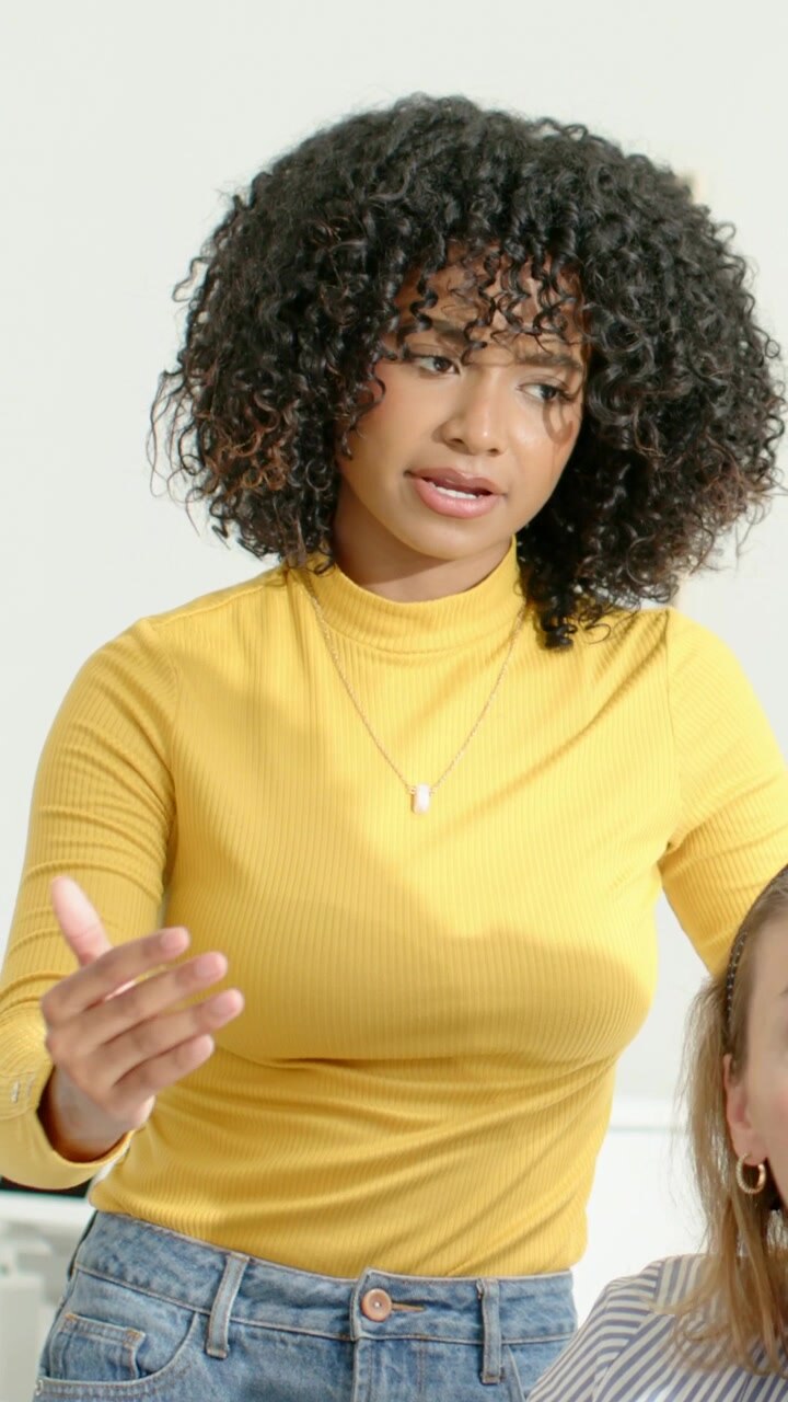 Vertical video: Woman in mustard top pointing, explaining for review as coworker tapping PC at desk
