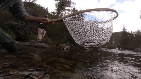 a man in his 60's is fly fishing in a creek