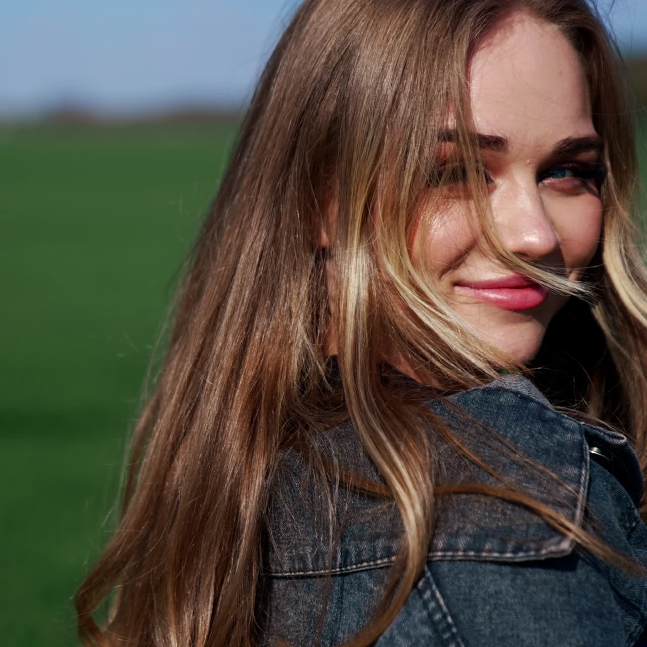 Pretty model on field. Facial portrait of beautiful blonde walking and smiling on camera. Happy young woman with blue eyes posing outdoors