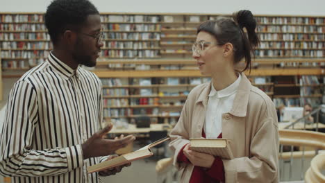 hombre y mujer multiétnicos hablando en la biblioteca