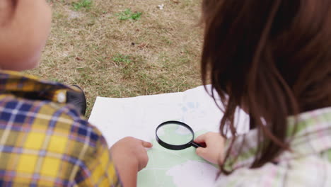 gruppe von kindern auf einer campingreise im freien, die gemeinsam nach einer karte schauen