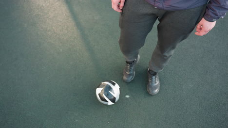 overhead view of athlete demonstrating precise ankle movements with soccer ball on ground, focusing on agility and control during a training session on textured sports surface in outdoor setting