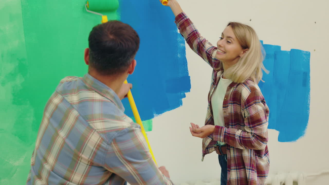 una pareja pintando una pared.