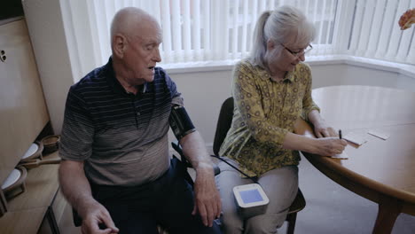 elderly couple checking blood pressure at home