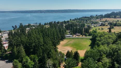 aerial shot above a forest with a baseball field clearing underneath on whidbey island