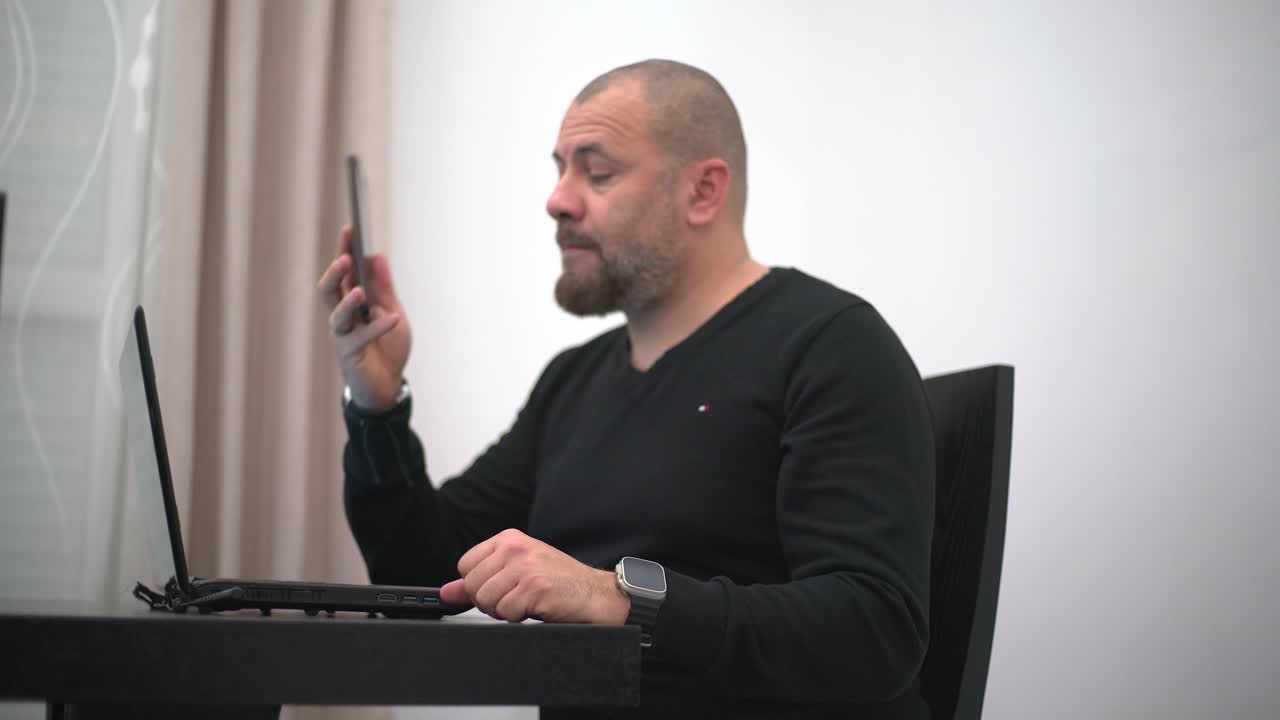 un hombre que trabaja con su computadora en casa y habla por teléfono