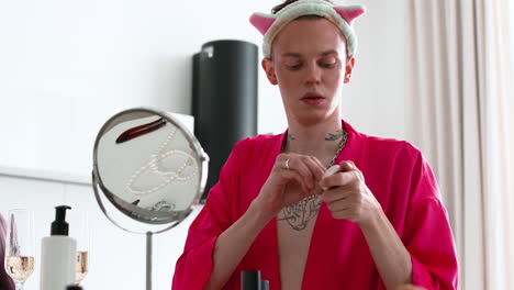 Queer-man-applying-makeup-in-the-kitchen