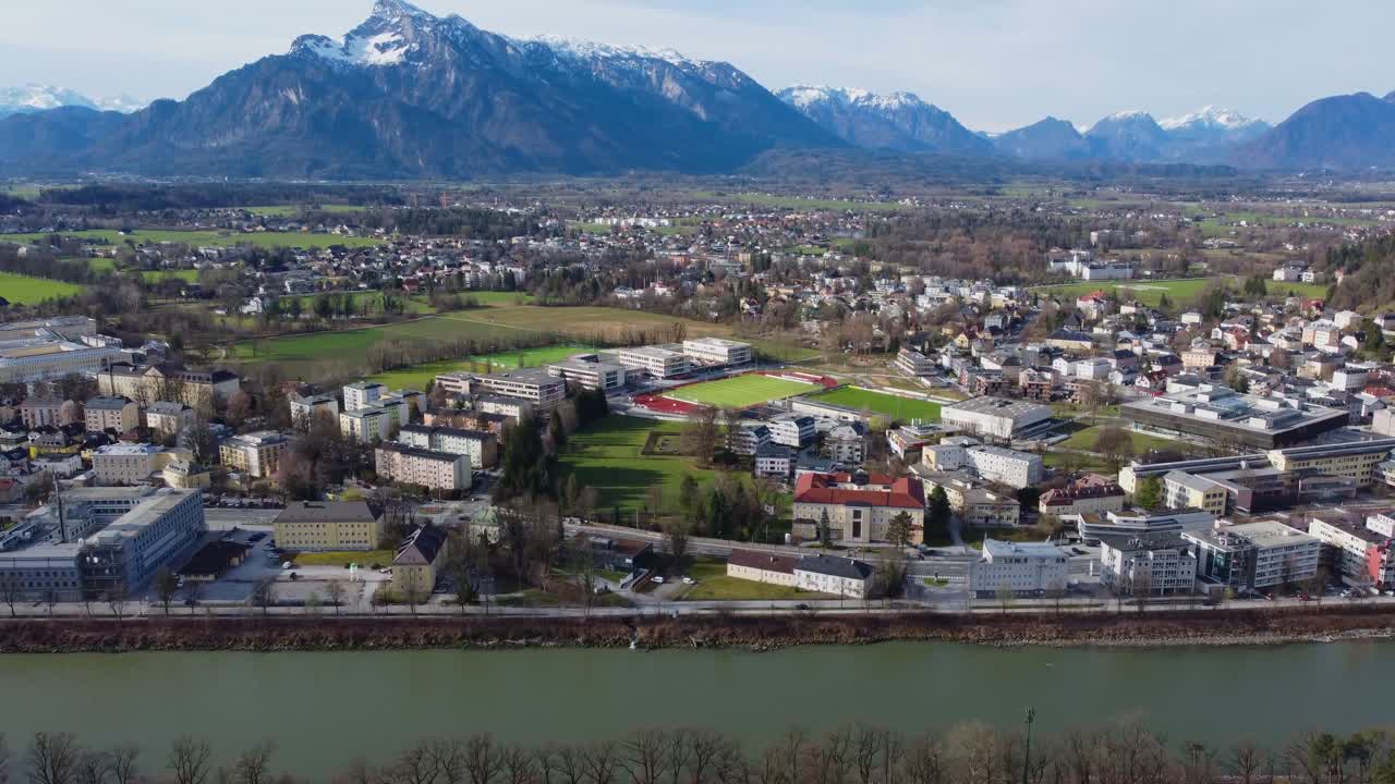 Cinematic reveal of snow-topped Alps towering over Salzburg City - Austria