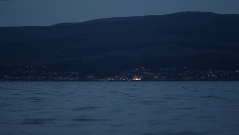 Luces-Costeras-De-La-Ciudad-Debajo-De-La-Ladera-Al-Borde-Del-Agua-En-La-Hora-Azul