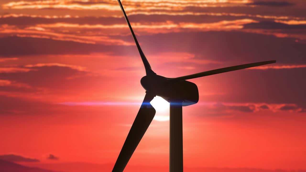 Silhouette of the wind turbine with big spinning blades against the red sunset