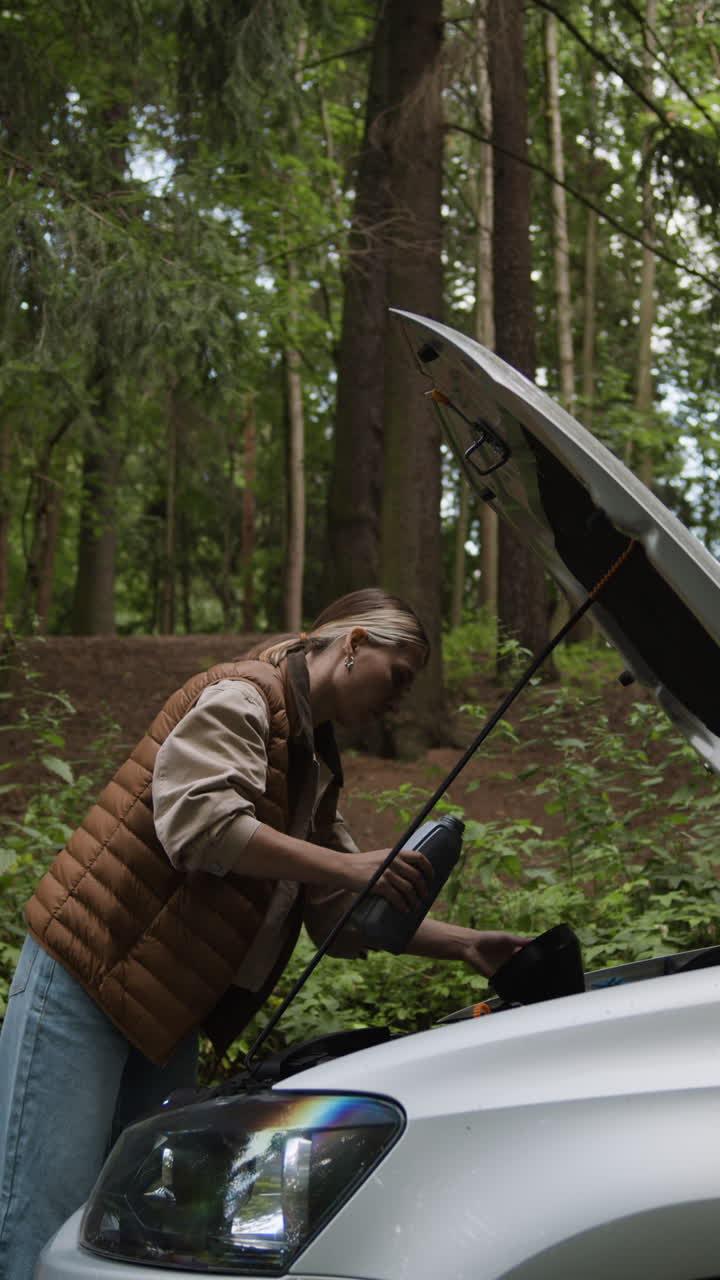 Woman Repairing Car in Forest