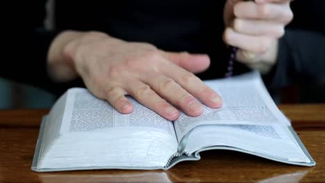 woman-praying-with-bible-on-table-with-black-background-with-people-stock-video