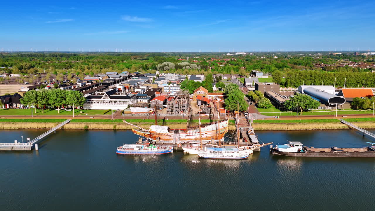 Reconstruction of the VOC ship Batavia surrounded by the smaller modern boats. Flying along the waterfront of Lelystad,the Netherlands. Aerial view.