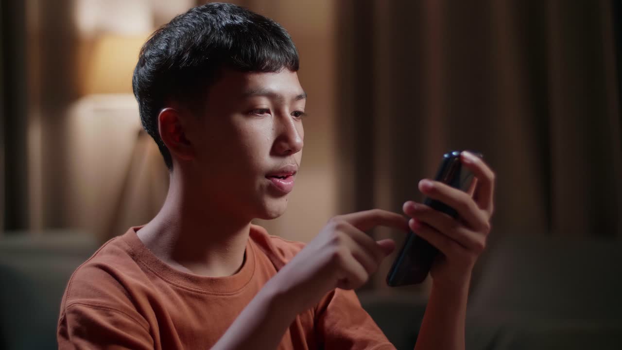 집에서 데스크 컴퓨터에서 작업하는 동안 스마트폰을 사용하는 아시아 소년 신발 디자이너의 클로즈업