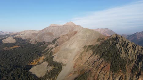 a high flying, slow rotating drone shot, of rocky mountain peaks near telluride, colorado, on a sunny day in the fall season