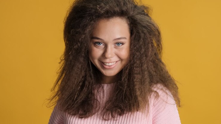 Donna caucasica con capelli ricci che sorride alla macchina fotografica