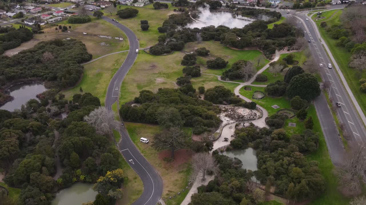 vehículos que conducen por la calle ranolf pasando por el paisaje térmico de kuirau cerca de agua caliente en ohinemutu, rotorua, nueva zelanda