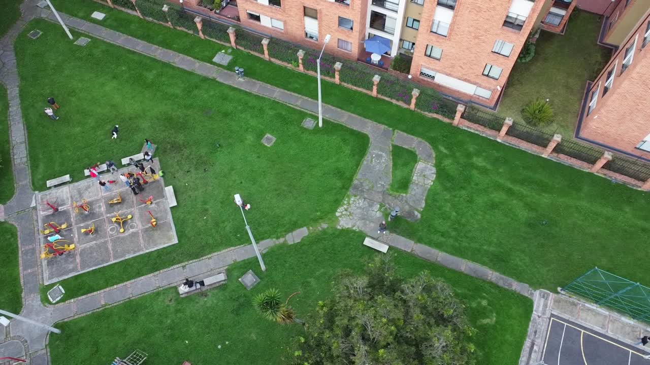 A drone shot flying over a park with people and their dogs
