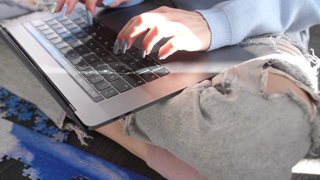 긴 손톱 매니큐어 타이핑을 하는 여성 현대적인 노트북 키워드 장치는 패션 찢어진 청바지를 입고 다리를 꼬고 앉아 있고, 인터넷 검색은 빠른 5g 연결을 연구하고, 여성 손은 슬로우 모션을 닫습니다.