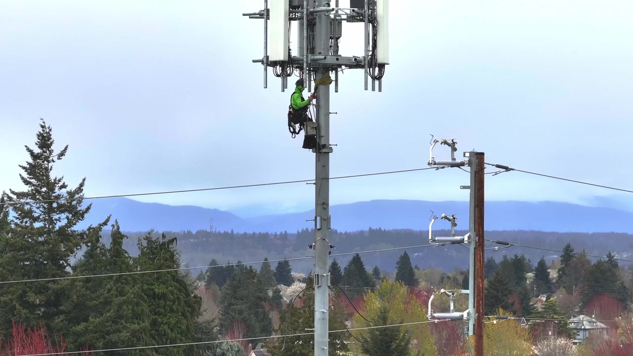 Der Techniker auf dem Mast repariert den Satelliten für den Internetdienst – Schwenk nach oben.