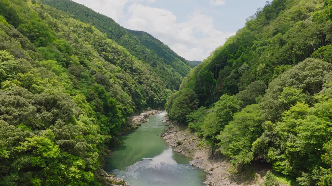 Aerial establishing landscape of Arashiyama River between Mountain green Forested Valley of Kyoto Japan