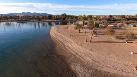 Aerial-view-of-a-drone-panning-out-from-a-beach-over-a-lake-on-a-sunny-day