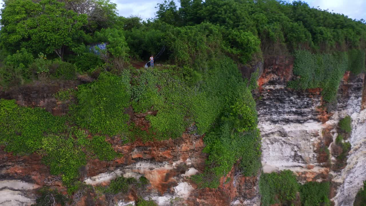 туристка стоит на краю скалы в улувату, бали, индонезия - воздушное отступление